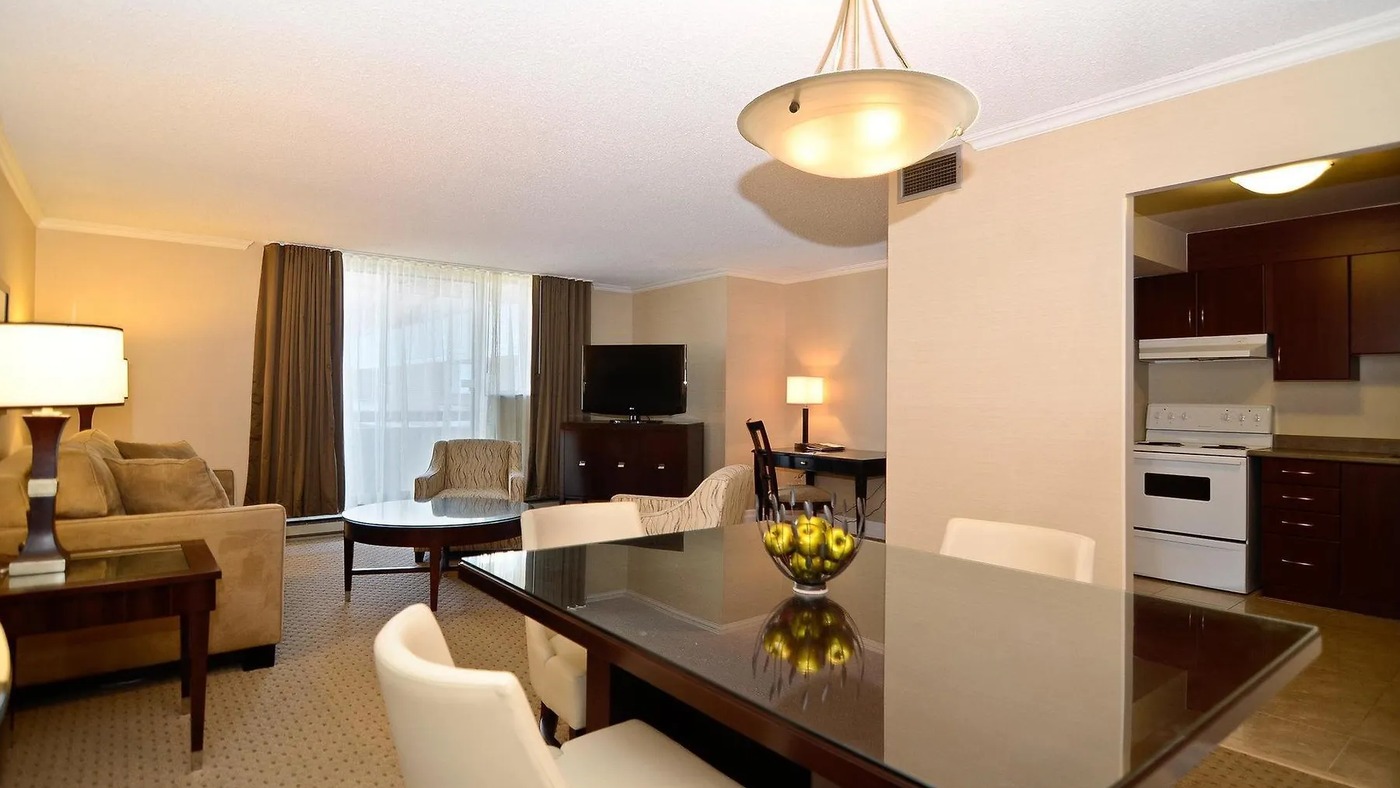Albert at Bay Suite Hotel living room — spacious suite with dining table, full kitchen visible through doorway, Ottawa